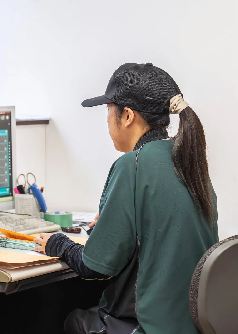 事務所でパソコンに向かい書類を確認するK.C.さん