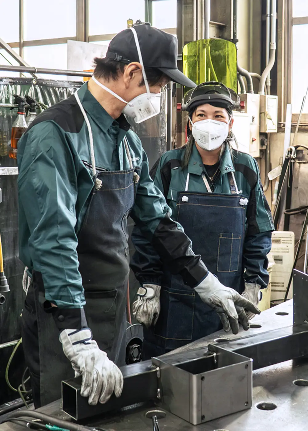 製造現場で先輩社員とともに作業するK.C.さん
