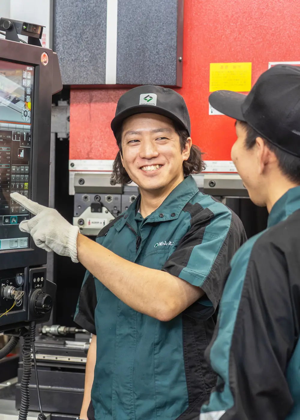 操作パネルの前でメンバーと打ち合わせるN.I.さん