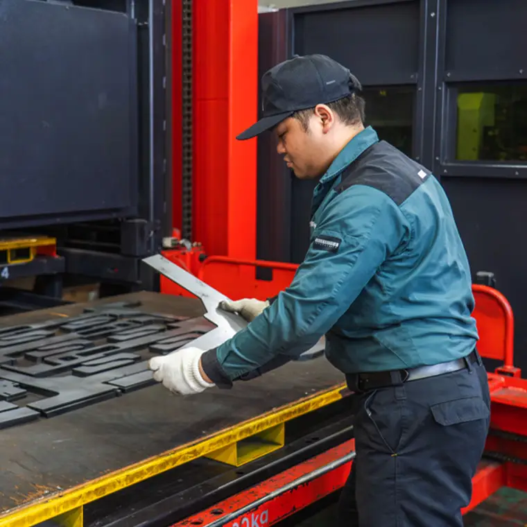 加工機から部品を取り出す社員